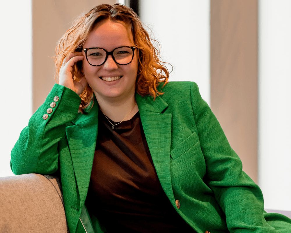 Foto van Jennifer Kok met een groen jasje aan zittend op een bank